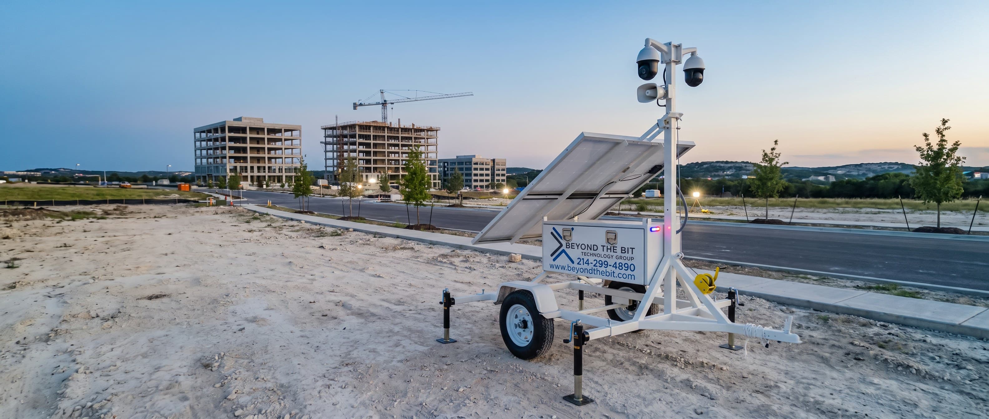 A Beyond the Bit security trailer standing at dusk beside a new office corridor under construction, limestone hills on the horizon — representative of the Austin growth-corridor sites we watch.