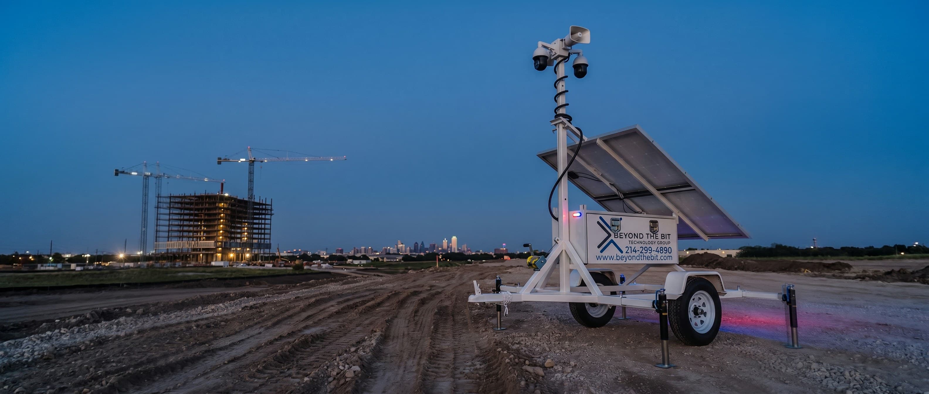A Beyond the Bit security trailer with raised camera mast standing on a Dallas construction site at dusk.