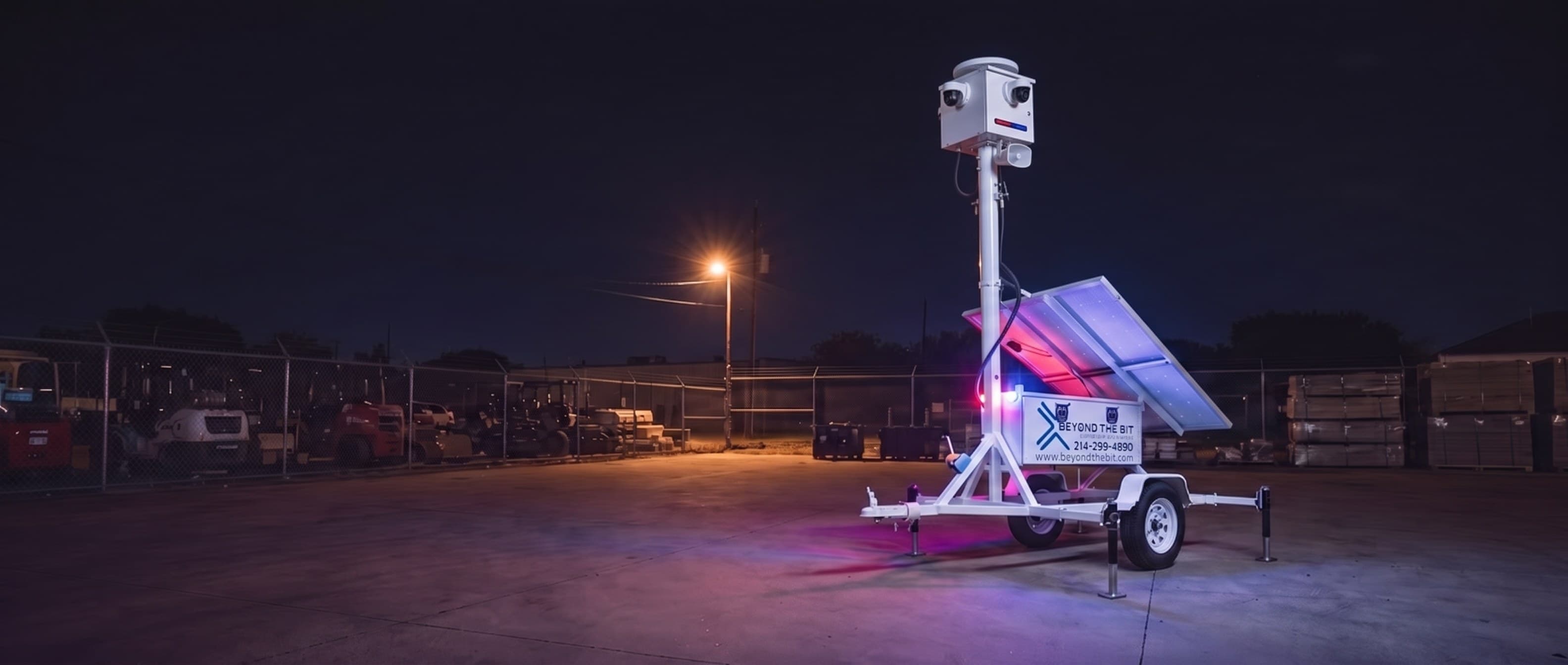 A Beyond the Bit security trailer at night with its blue strobe lit and camera mast raised against a dark sky, the kind of visible, continuous coverage that doesn't change when the sun goes down.