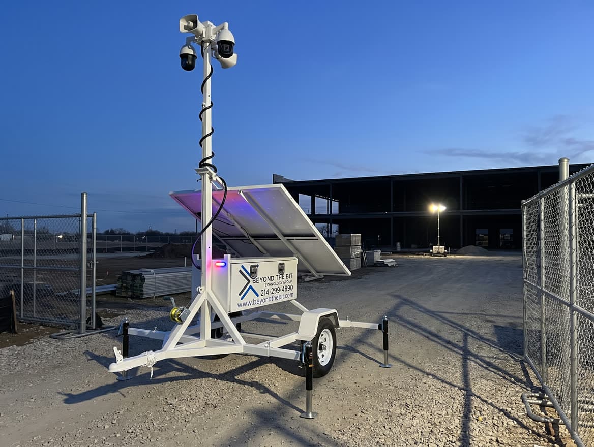 A Beyond the Bit security trailer parked inside a construction site gate at dusk, camera mast raised over the entrance road.