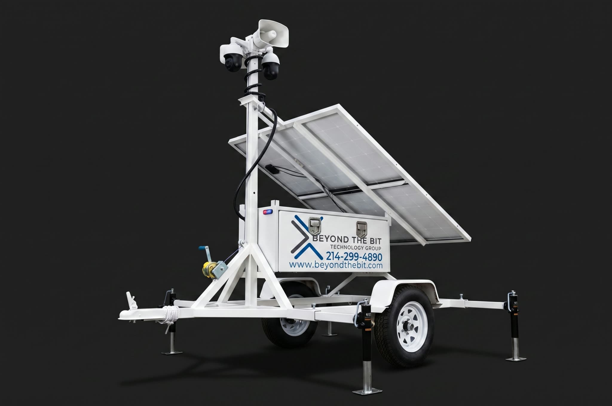 Studio view of a Beyond the Bit security trailer showing the raised camera mast, solar panels, and strobe against a dark background.