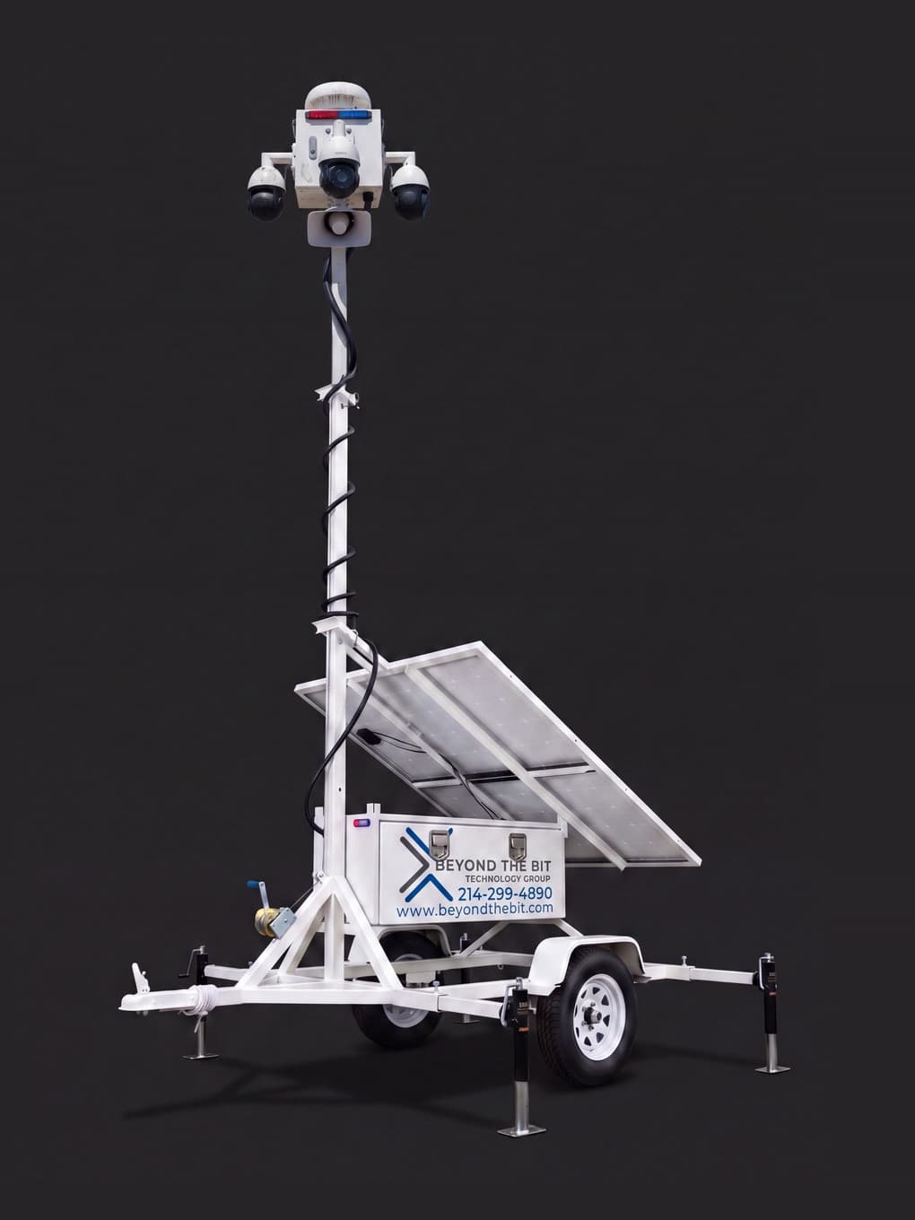 A Beyond the Bit security trailer photographed in a dark studio: white equipment box, fully raised telescoping camera mast, dual solar panels, and stabilizer jacks.